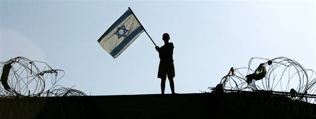 Image: A lone boy holds an Israeli flag atop the roof of the synagogue in the Jewish settlement of Kfar Darom on Friday.